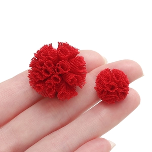 Détail de pompons en tulle rouge pour bijoux DIY tenus à la main pour l'échelle