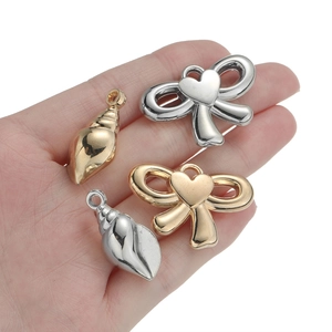 Goldene und silberne Schleifen- und Schneckenanhänger für DIY-Schmuck in der Hand