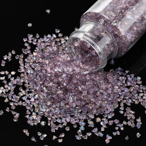 Macro shot of 30g purple iridescent crushed glass stones pouring from a clear bottle