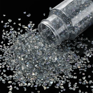 Macro shot of silver iridescent glass gravel pouring from bottle for DIY nail art and crafts