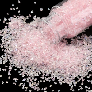 Macro view of 30g iridescent pink glass crushed stone pouring from a clear jar
