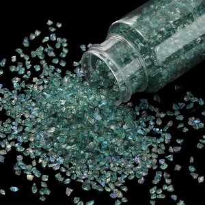 Macro shot of 30g iridescent green glass glitter for nail art and DIY crafts in a jar