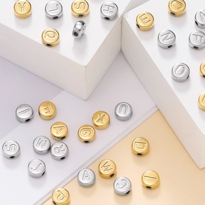Gros plan de perles alphabet de 7mm en acier inoxydable or et argent pour bijoux DIY