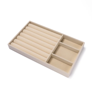 Detailweergave van beige fluwelen sieradendisplay met ringrollen en opbergvakken