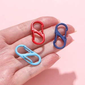 Tre moschettoni colorati a forma di S in rosso e blu tenuti su uno sfondo rosa