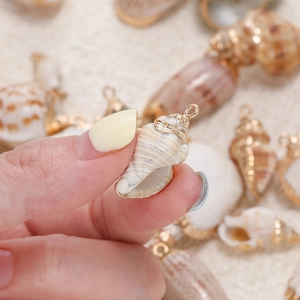 Makro-Detail von natürlichem Kaurimuschel-Anhänger mit vergoldetem Rand für DIY-Schmuck