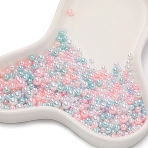 Mix of colorful round ABS faux pearls in pink blue and white on a ceramic tray