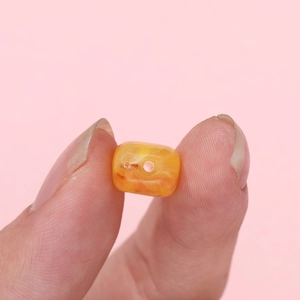 Close-up of an orange marble acrylic bead held by hand for DIY jewelry making size scale