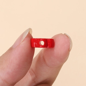 Primer plano de una pequeña cuenta cilíndrica de acrílico rojo con superficie lisa y agujero