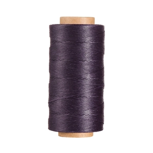 Dettaglio del filo di poliestere cerato viola scuro da 0,8 mm su una bobina di carta kraft