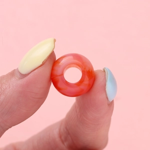 Detailopname van oranje-rode acryl kraal met verloop voor het maken van DIY-sieraden
