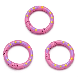 Detail van drie roze ronde veerringen met paarse en gele stippen voor DIY-sieraden