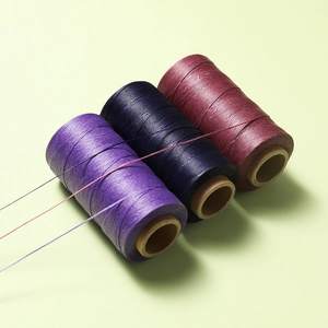 Vista dettagliata di fili di poliestere cerato da 0,8 mm viola, blu navy e rossi per pelle