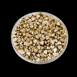 Gros plan de perles dorées en forme de cœur et d'étoile dans un boîtier en plastique