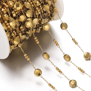 Detail of gold oval link chain with small beads on a spool for DIY jewelry making
