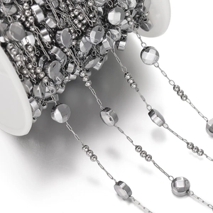 Macro shot of silver stainless steel chain with beads and sequins on a spool for DIY jewelry