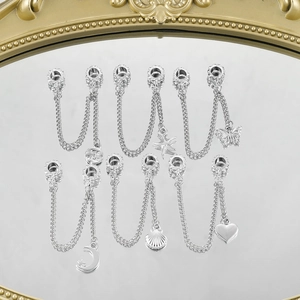 Dettaglio di catene di sicurezza in argento con ciondoli stella, luna e cuore per bracciali