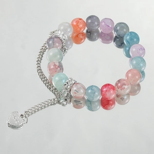 Dettaglio di un braccialetto di perle colorate con ciondolo a cuore argento inciso LOVE