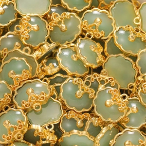 Macro detail of Chinese Ruyi pendants with green chalcedony and gold cloud patterns