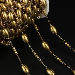 Macro detail of golden stainless steel oval and round bead chain on white spool