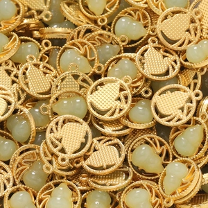 Macro detail of gold-framed light green gourd charms for DIY jewelry making and crafts