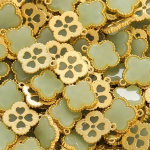 Macro shot of gold-plated clover jewelry pendants with light green faux jade inlay
