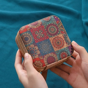 Joyero portátil con diseño de mandala y textura de corcho sostenido en la mano