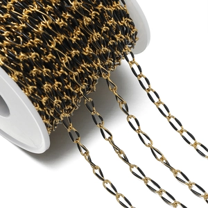 Macro view of gold-plated oval chain links with black enamel finish on a white spool