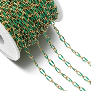 Detailed macro view of gold-plated oval chain links with green enamel coating on a reel