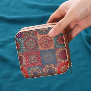 Joyero portátil con diseño de mandala en cuero marrón y cremallera dorada en la mano