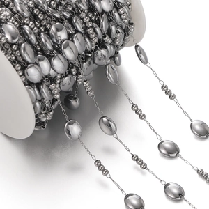 Macro view of gunmetal oval bead chain on a white reel for DIY jewelry making