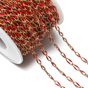 Macro detail of red enamel and gold-plated stainless steel oval chain on a white spool
