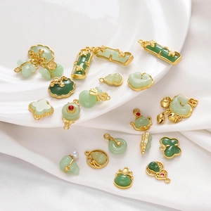 Flat lay of Chinese style green jade-like pendants with gold-plated alloy frames on white silk