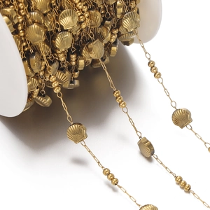 Detailed view of golden chain spool with shell pendants and beads for DIY jewelry making
