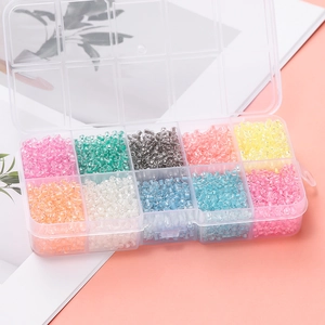 Close-up of 10-color luminous glass seed beads in a transparent plastic organizer box