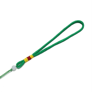Détail du cordon tissé vert avec perle blanche et fils colorés pour bijoux artisanaux
