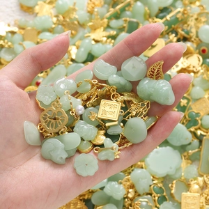 Detail of green faux jade and gold alloy pendants with traditional Chinese charms