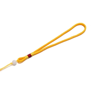 Détail de la corde tressée jaune vif avec fil rouge enroulé et perle ronde blanche