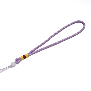 Vue détaillée du cordon tressé violet fait main avec une perle blanche et du fil de soie coloré