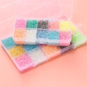 Macro shot of 3mm luminous glass seed beads in divided plastic storage containers for DIY