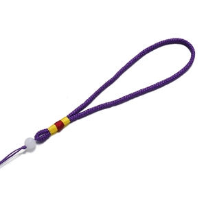 Gros plan sur cordon tressé violet avec perle blanche et nœuds décoratifs colorés