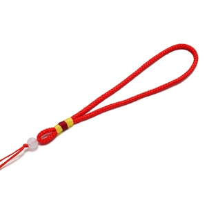 Détail du cordon tressé rouge avec perle blanche translucide et décorations en soie