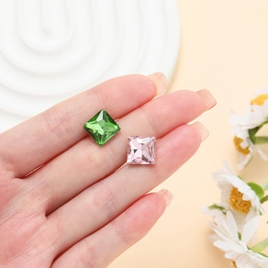 Detail of square princess cut glass crystals in olive and pink on fingertips