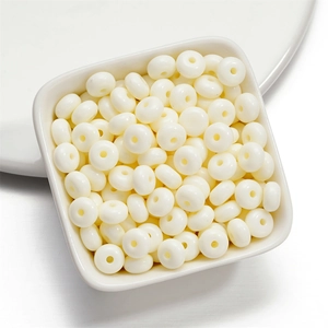 Flat round acrylic beads in cream white on a ceramic tray for DIY jewelry making