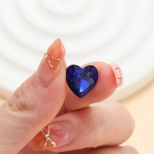 Vista macro di un cristallo a forma di cuore blu scuro per nail art e gioielleria