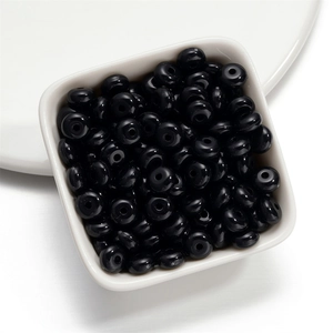 Macro shot of 8mm glossy black acrylic wheel beads in a white bowl for DIY jewelry
