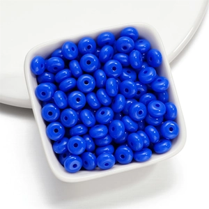Close-up of vibrant blue acrylic spacer beads in a white bowl for DIY jewelry making