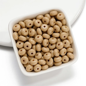 Macro shot of milk-tea colored acrylic flat round spacer beads in a white ceramic bowl