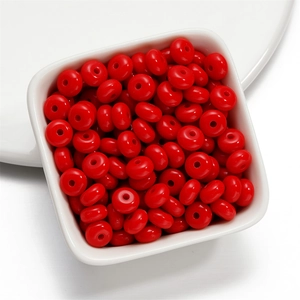 Close-up of 8mm red acrylic spacer beads in a white bowl for DIY jewelry making