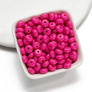 Detailed view of glossy rose red acrylic spacer beads in a white tray for jewelry making